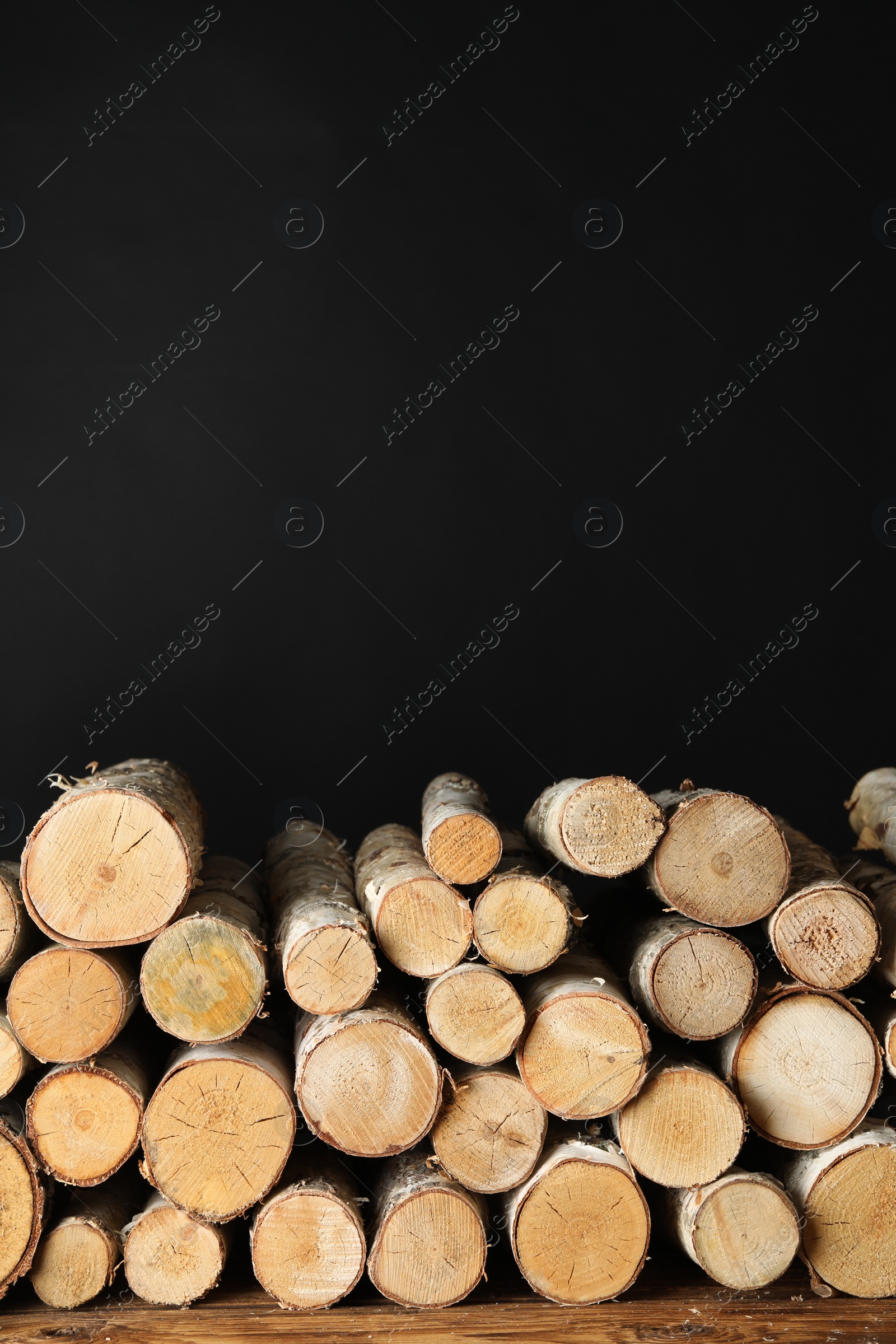 Photo of Cut firewood on table against black background