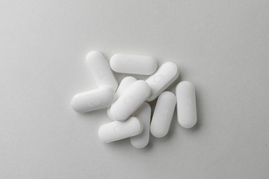 Photo of Pile of calcium supplement pills on light grey background, flat lay