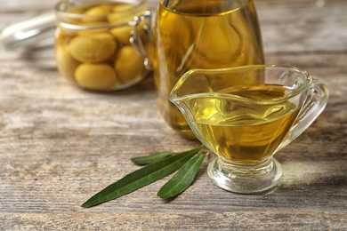 Photo of Gravy boat with fresh olive oil on wooden table, closeup