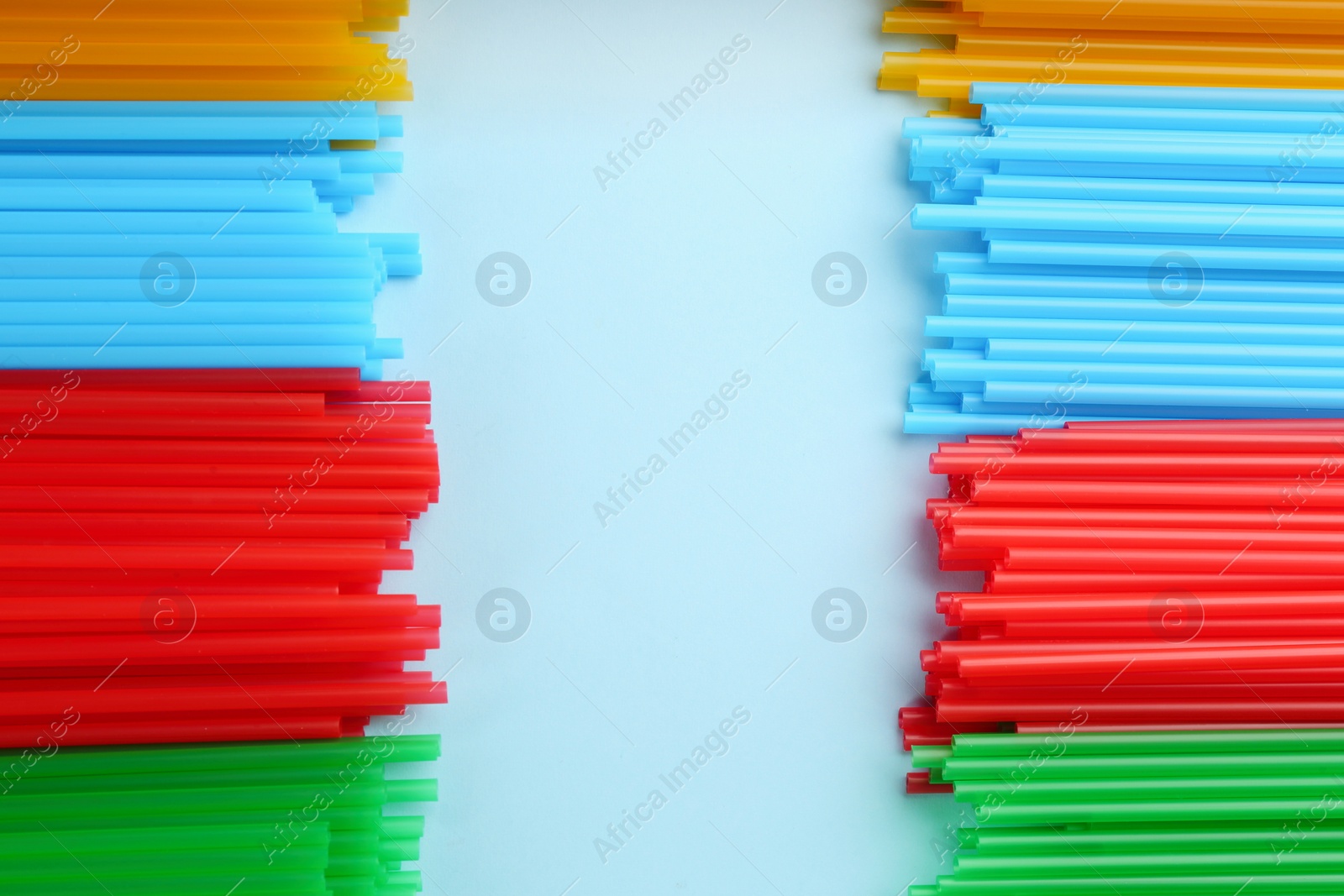 Photo of Heap of colorful plastic drinking straws on light blue background, flat lay. Space for text