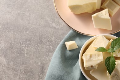 Photo of Pieces of tasty white chocolate and mint on grey table, top view. Space for text