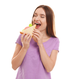 Young woman eating tasty sandwich on white background