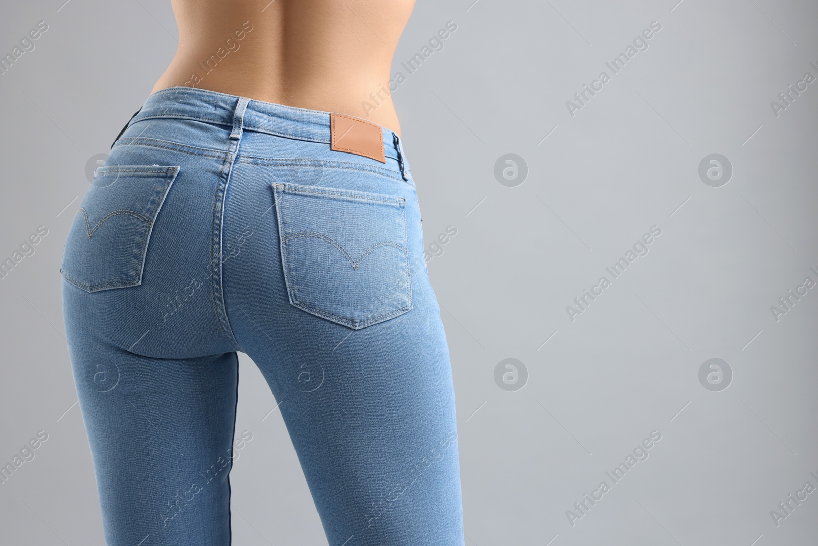 Photo of Woman wearing stylish jeans on light gray background, closeup. Space for text