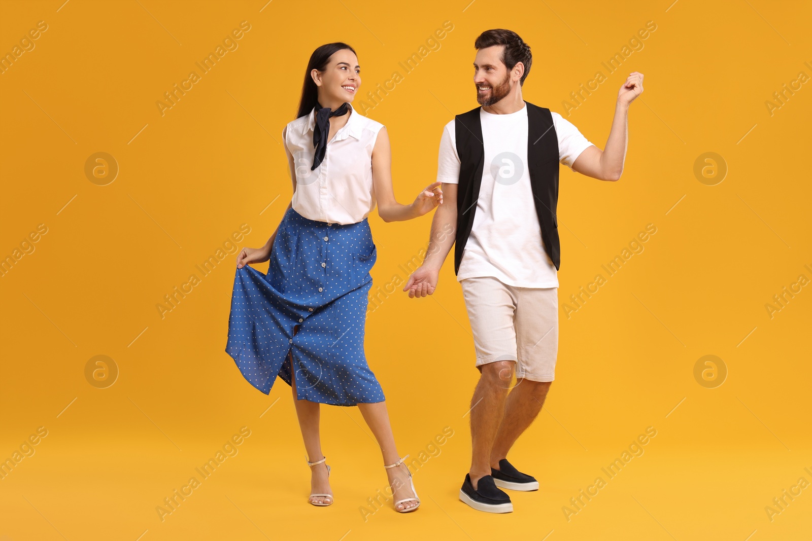 Photo of Happy couple dancing together on orange background