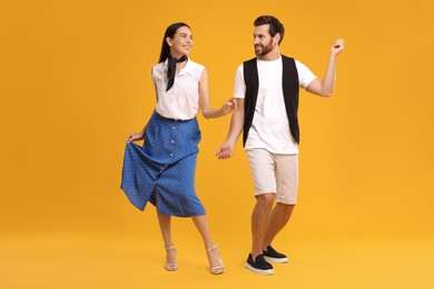 Photo of Happy couple dancing together on orange background