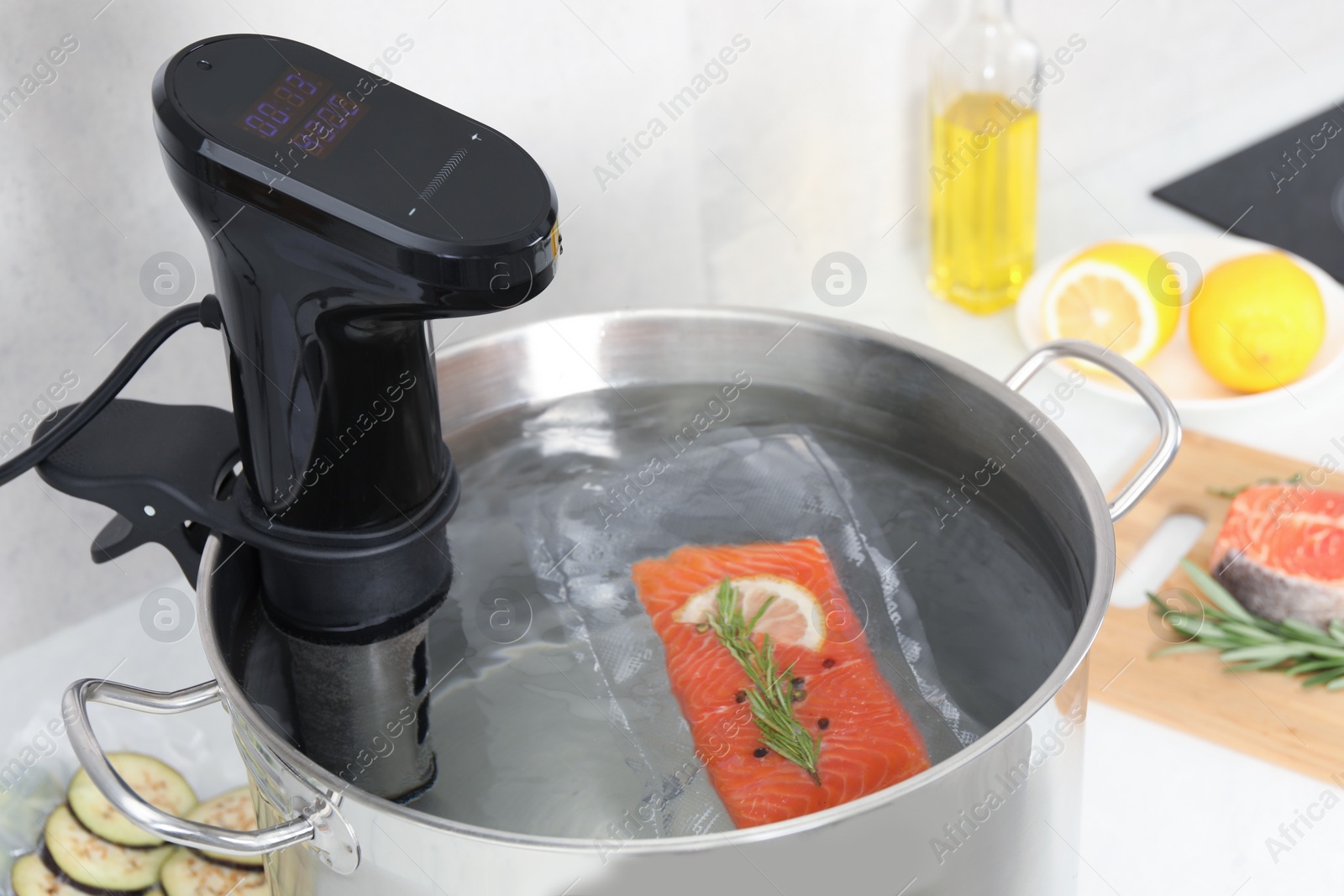 Photo of Sous vide cooker and vacuum packed salmon in pot on table, closeup. Thermal immersion circulator