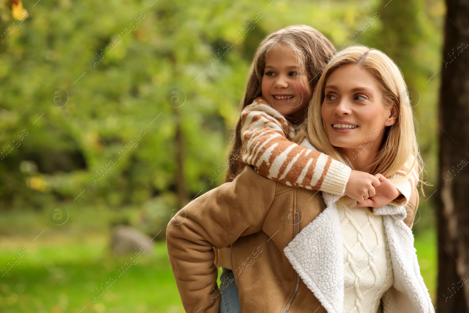 Photo of Happy mother walking with her daughter in autumn park, space for text