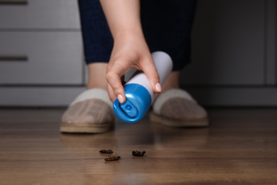 Photo of Woman spraying insecticide onto cockroaches, closeup. Pest control