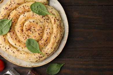 Photo of Delicious puff pastry with spinach on wooden table, top view. Space for text