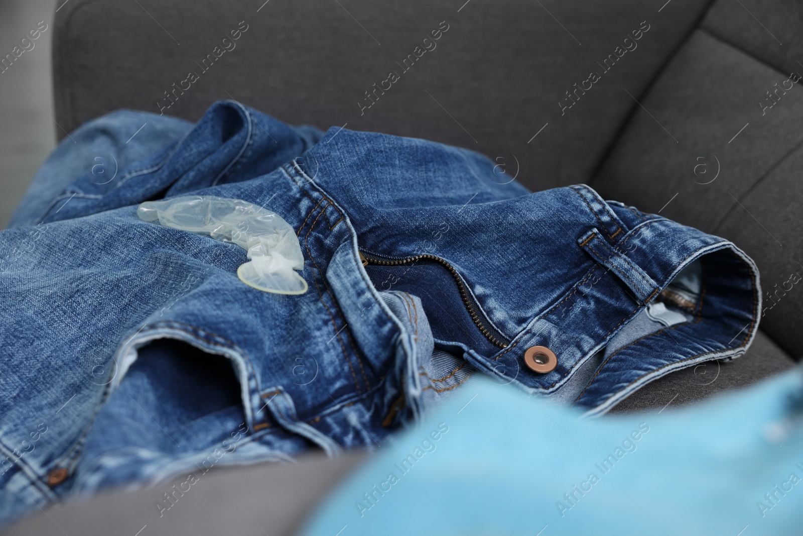 Photo of Unrolled condom and jeans on armchair. Safe sex