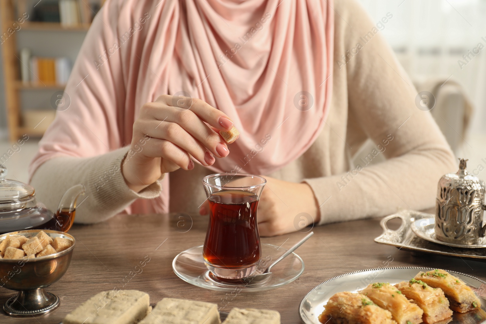 Photo of Woman with cup of delicious Turkish tea at wooden table, closeup