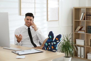 Photo of Businessman in shirt and underwear talking on mobile phone near computer at home office