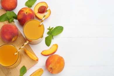 Photo of Natural peach juice and fresh fruits on white wooden table, flat lay. Space for text