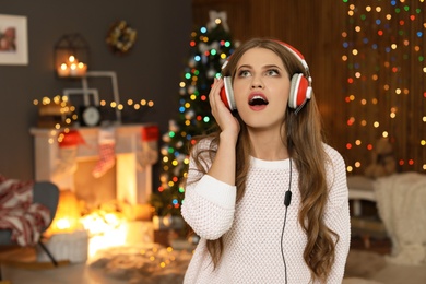 Photo of Happy young woman listening to Christmas music at home