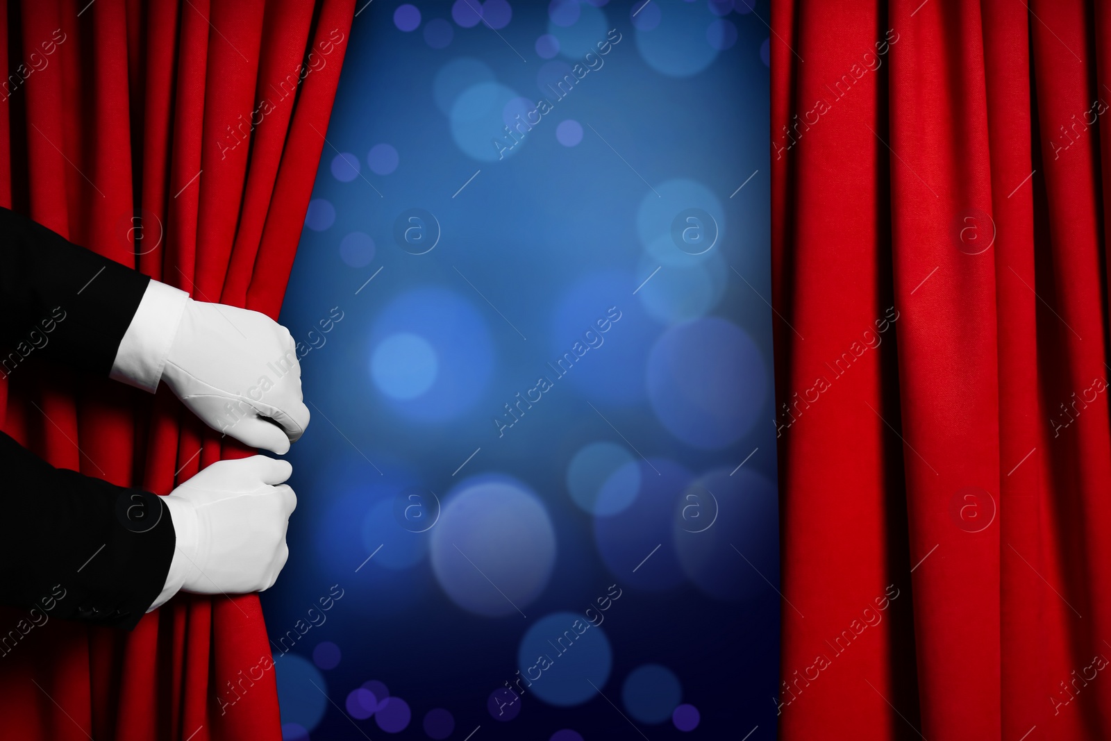 Image of Man opening red front curtains against blurred lights. Bokeh effect 