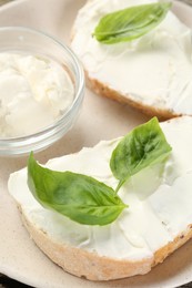 Photo of Delicious sandwiches with cream cheese and basil leaves on wooden table
