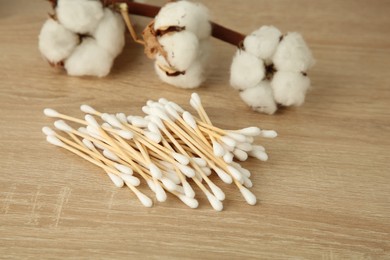 Photo of Cotton swabs and flowers on wooden table, closeup