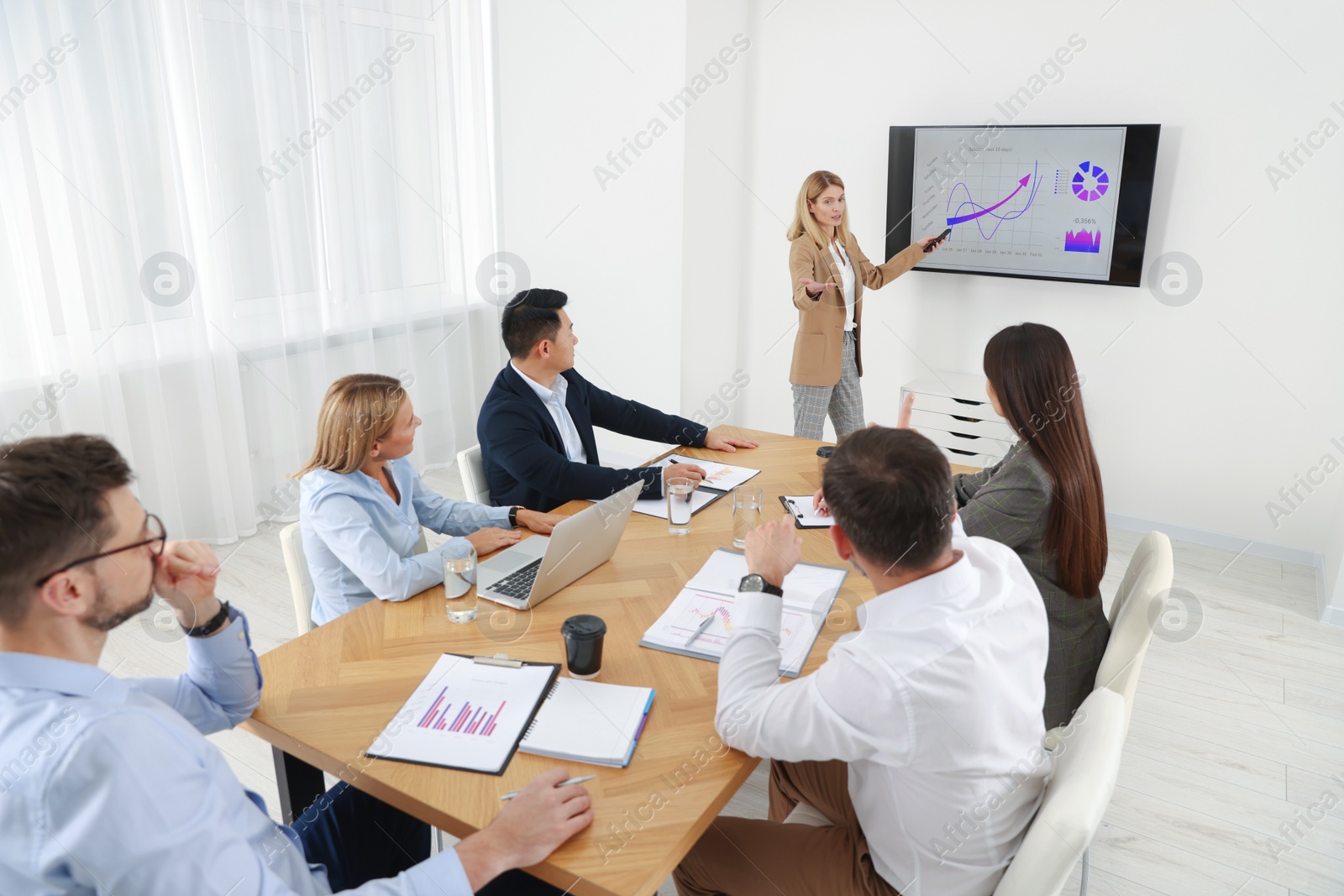 Photo of Businesswoman showing charts on tv screen in office