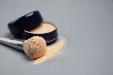 Photo of Loose face powder and makeup brush on light grey background, closeup. Space for text