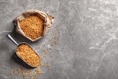 Scoop and bag with brown sugar on table