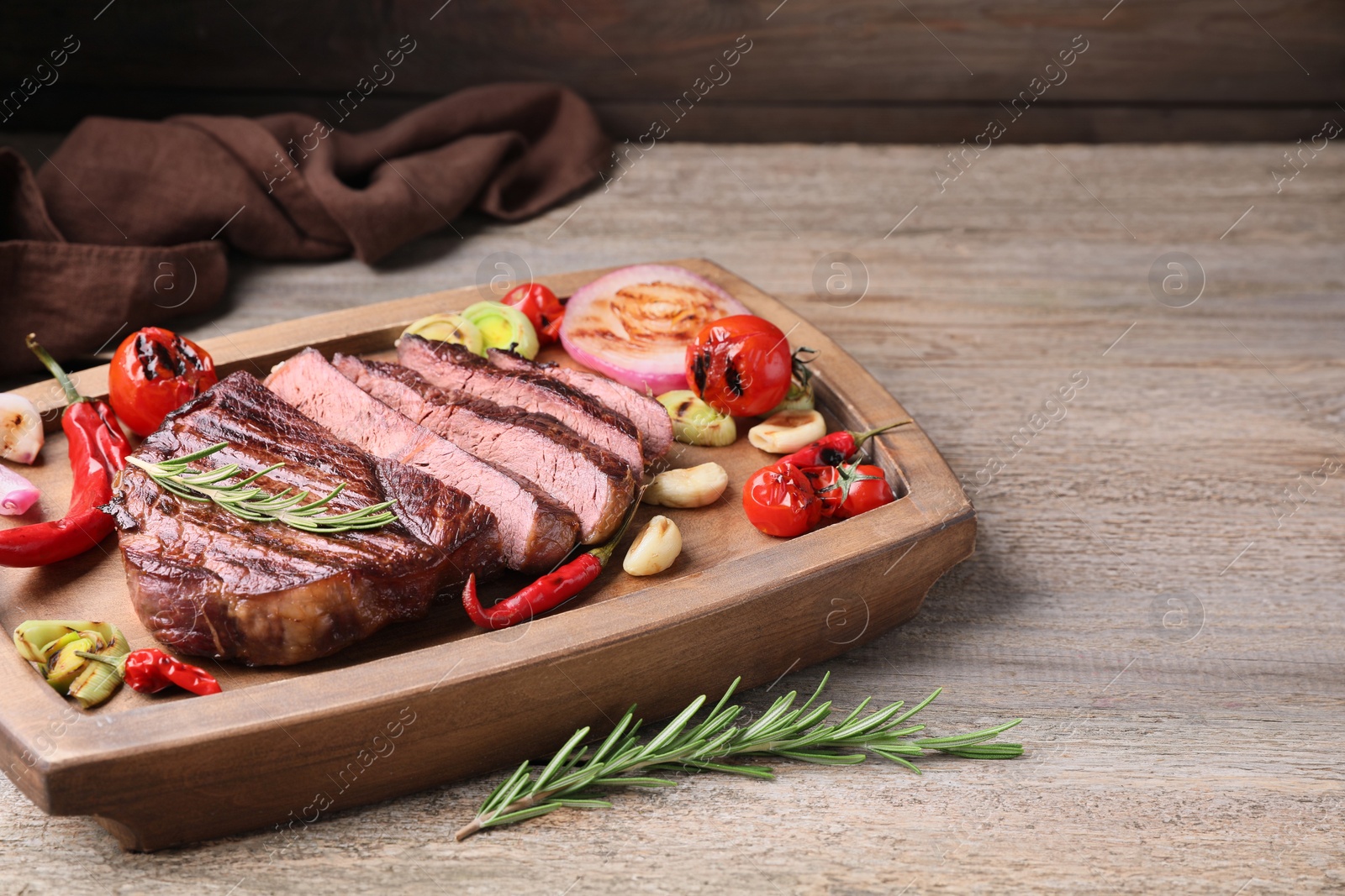 Photo of Delicious fried beef meat served with vegetables on wooden table. Space for text