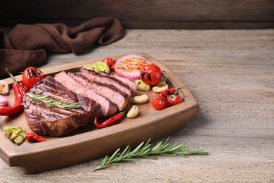 Delicious fried beef meat served with vegetables on wooden table. Space for text