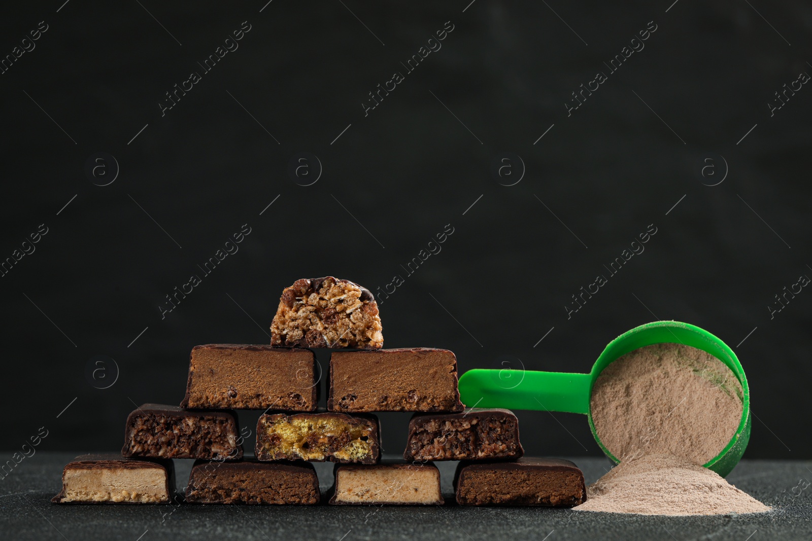 Photo of Different tasty energy bars and protein powder on grey table, space for text