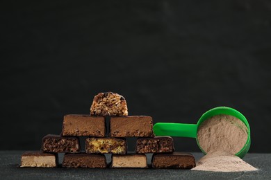 Photo of Different tasty energy bars and protein powder on grey table, space for text