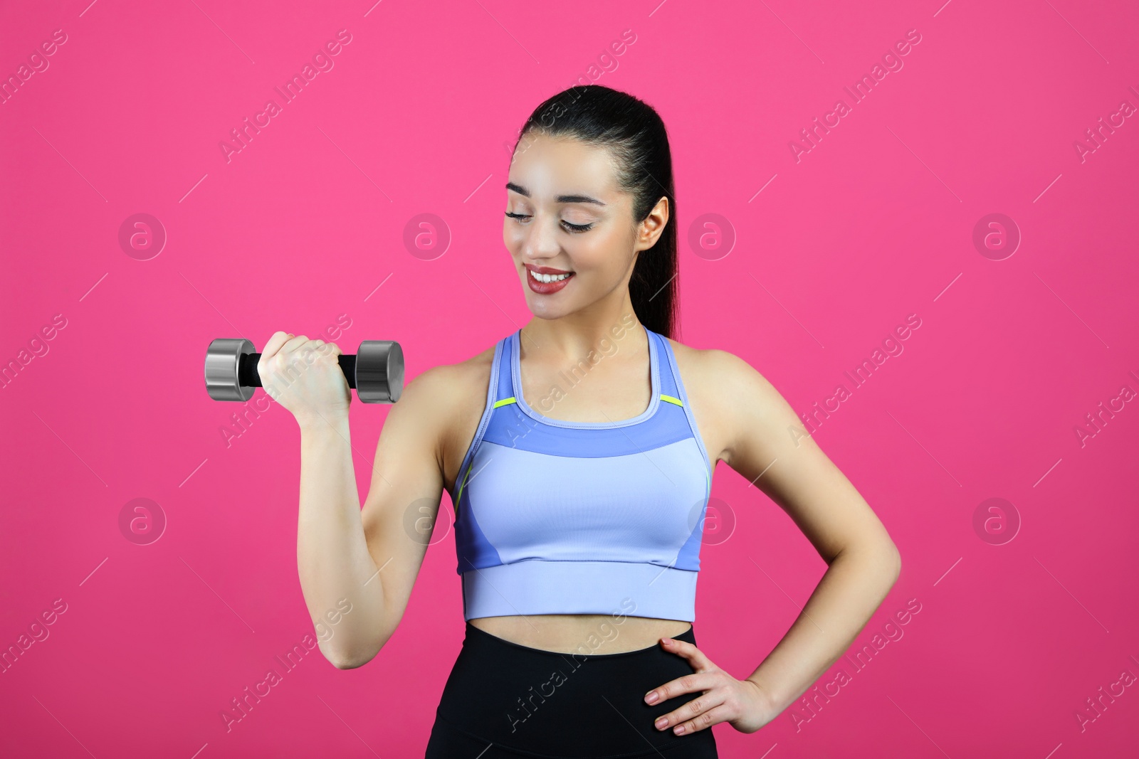Photo of Woman with dumbbell as girl power symbol on pink background. 8 March concept