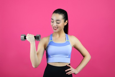 Woman with dumbbell as girl power symbol on pink background. 8 March concept