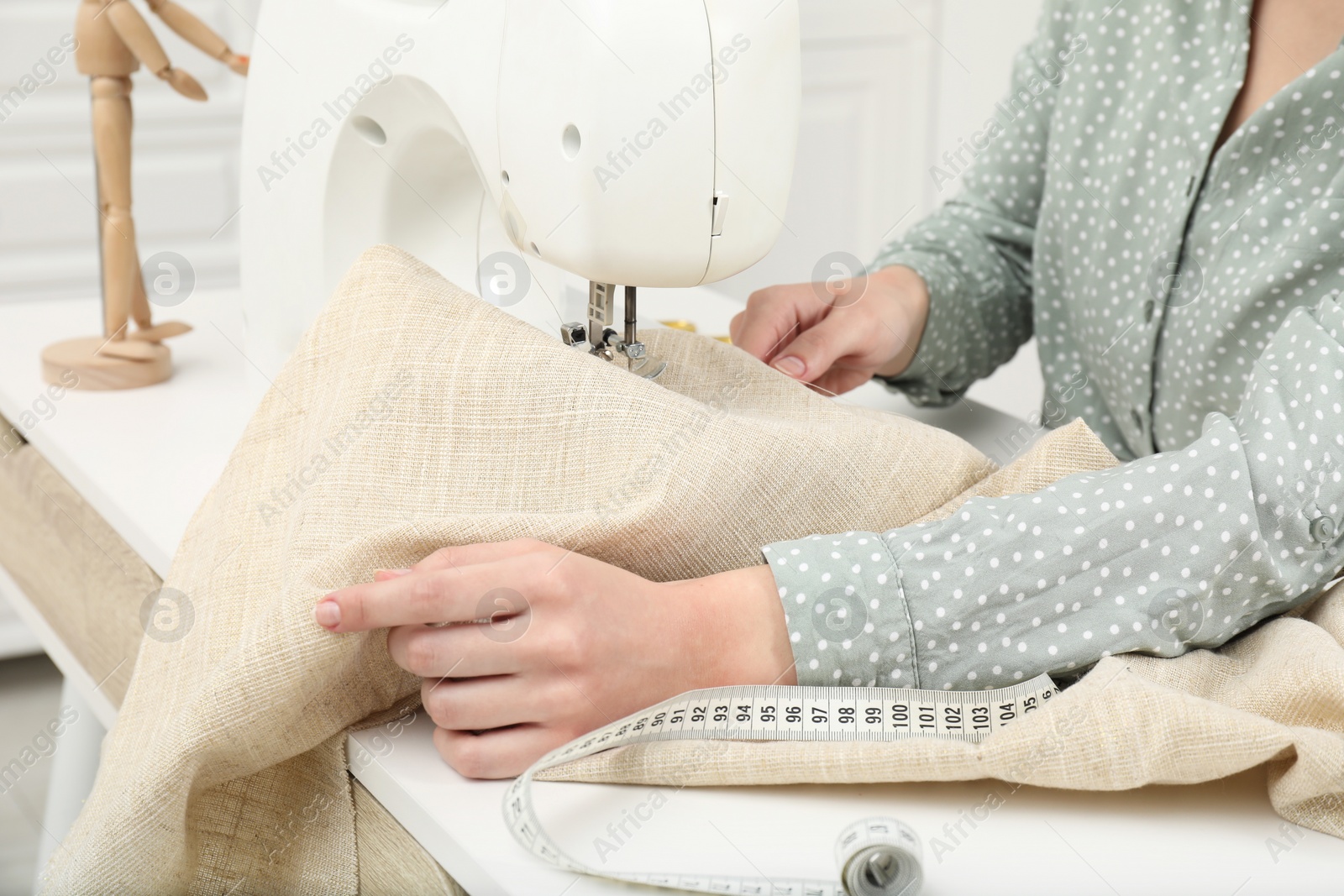 Photo of Seamstress working with sewing machine indoors, closeup