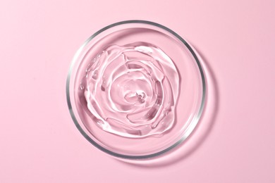 Photo of Petri dish with liquid on pale pink background, top view