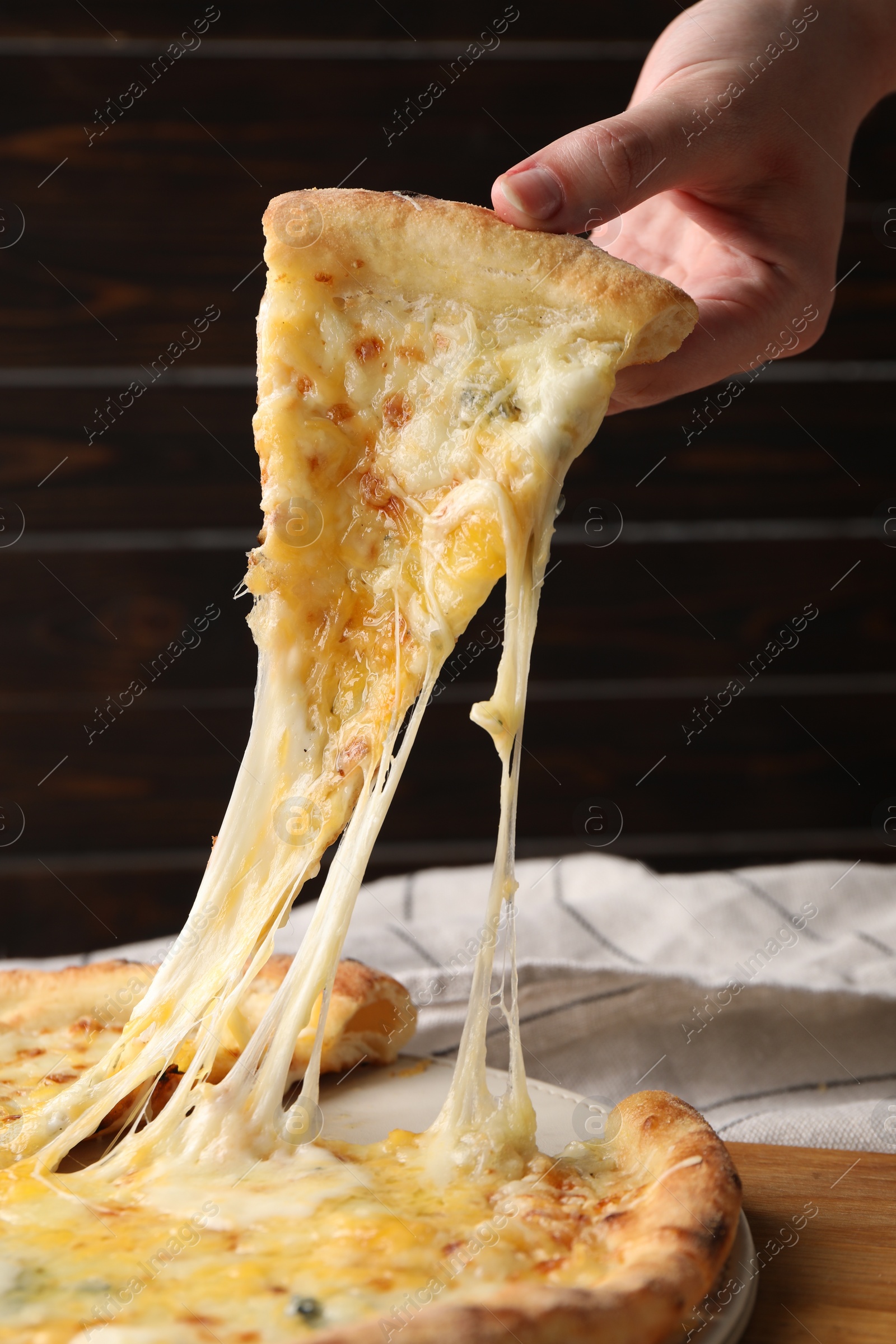 Photo of Woman taking piece of delicious cheese pizza at table, closeup