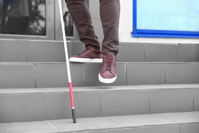Photo of Blind person with cane going down stairs outdoors, closeup
