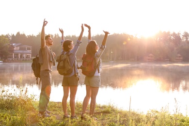 Young friends on shore of beautiful lake. Camping season