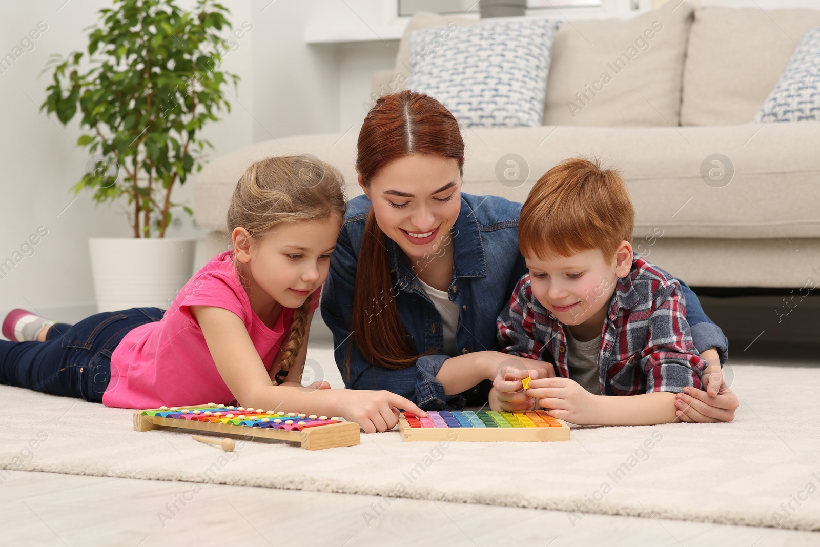 Photo of Happy mother and children playing with different math game kits on floor in room. Study mathematics with pleasure