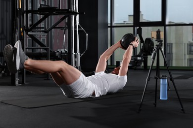 Photo of Trainer streaming online workout with phone at gym