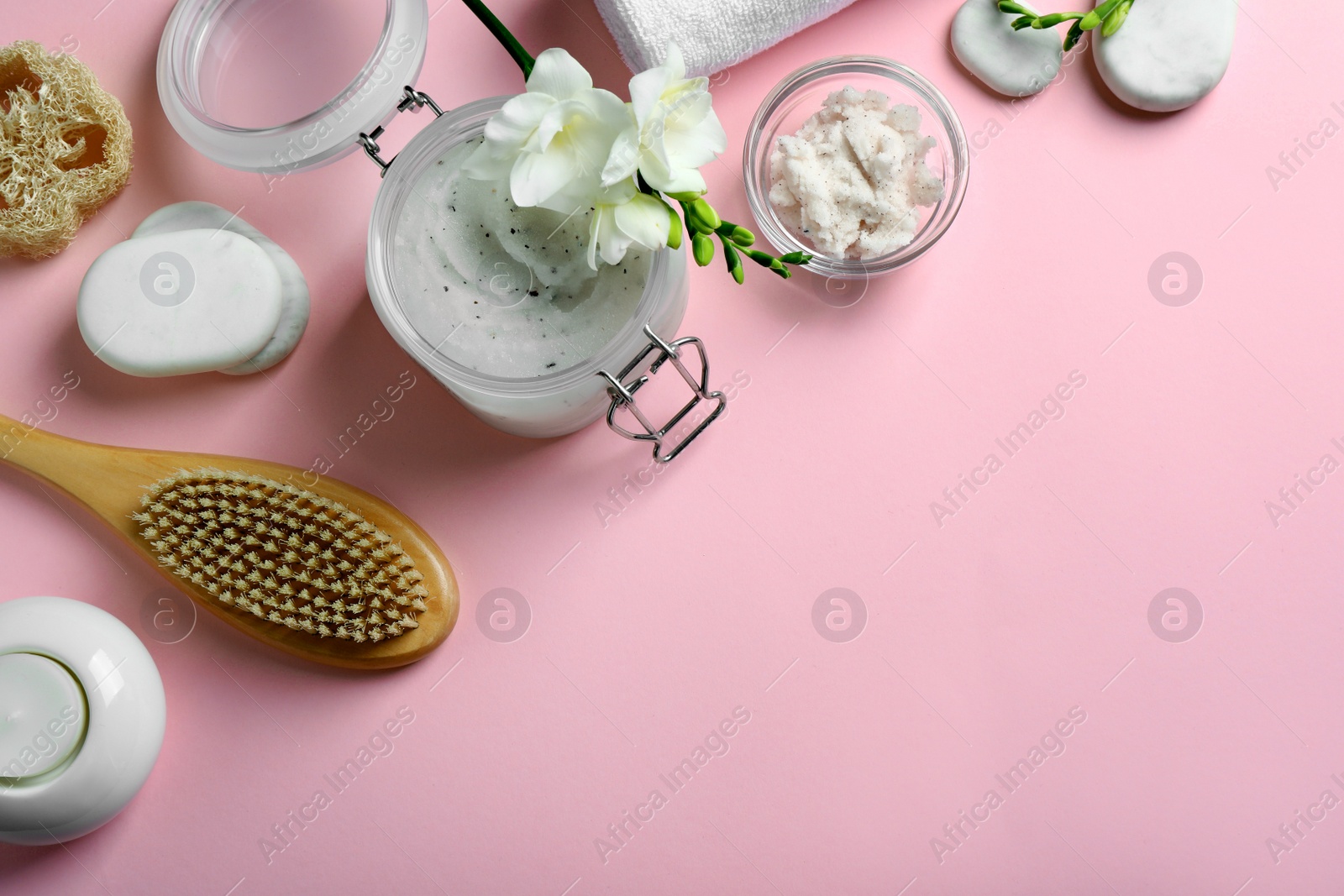 Photo of Flat lay composition with body scrub and freesia flowers on pink background, space for text