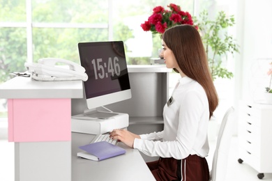 Beauty salon receptionist using computer at desk