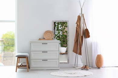 Photo of Modern hallway interior with chest of drawers and clothes on hanger stand