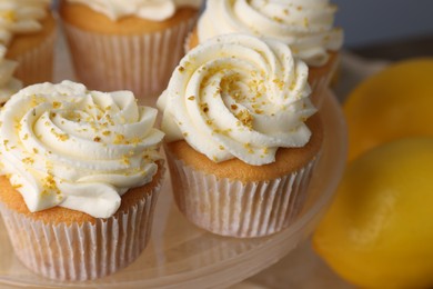 Delicious lemon cupcakes with white cream on stand, closeup
