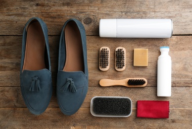 Stylish footwear with shoe care accessories on wooden table, flat lay