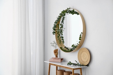 Photo of Round mirror and table with accessories near white wall. Modern interior design