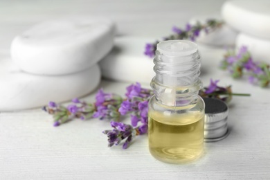 Photo of Bottle with natural lavender essential oil on white wooden table. Space for text
