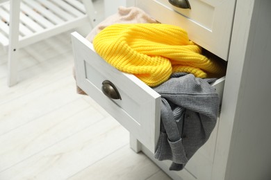 Cluttered chest of drawers indoors. Clothes in mess