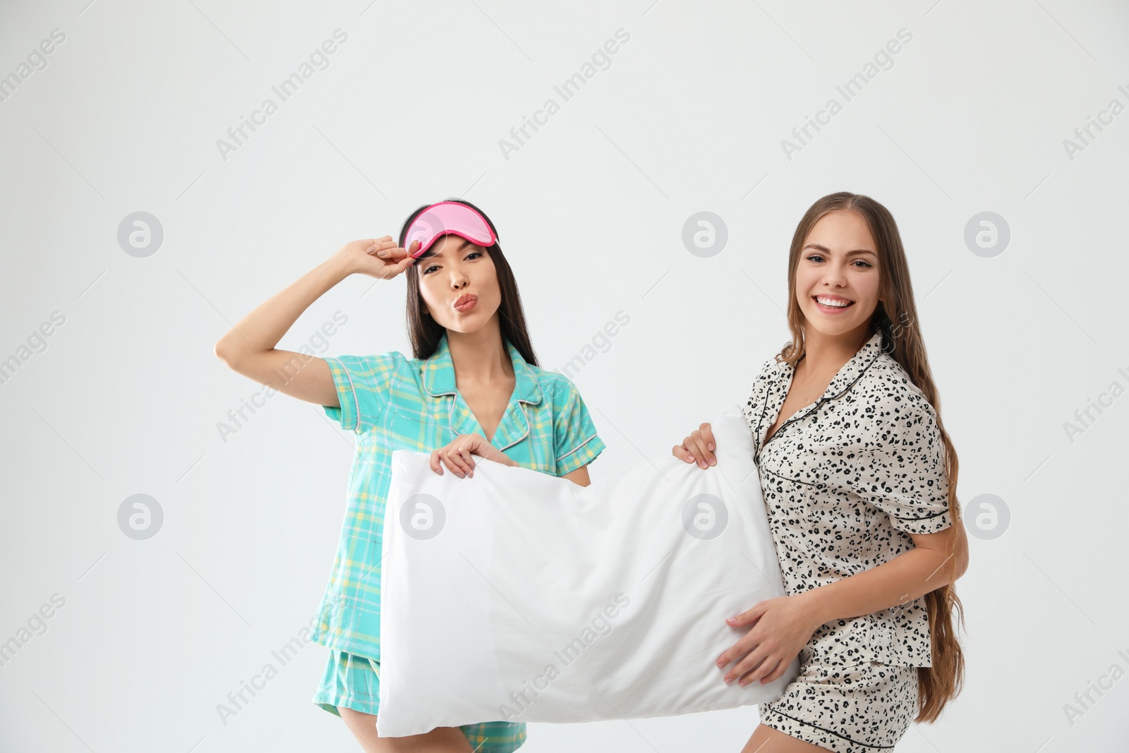Photo of Beautiful women in pajamas with pillow on light grey background. Bedtime