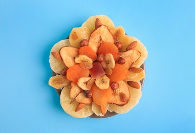 Mixed dried fruits and nuts on light blue background, top view