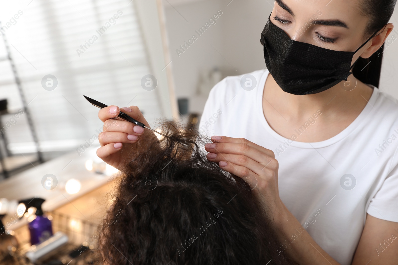 Photo of Professional stylist working with client in salon, closeup. Hairdressing services during Coronavirus quarantine