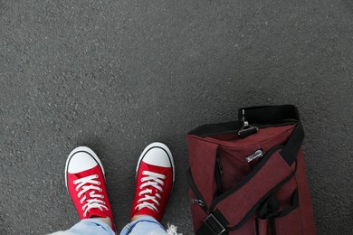 Photo of Woman with bag standing on asphalt, top view. Space for text