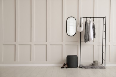 Photo of Simple hallway interior with clothing rack, mirror and empty wall. Space for design